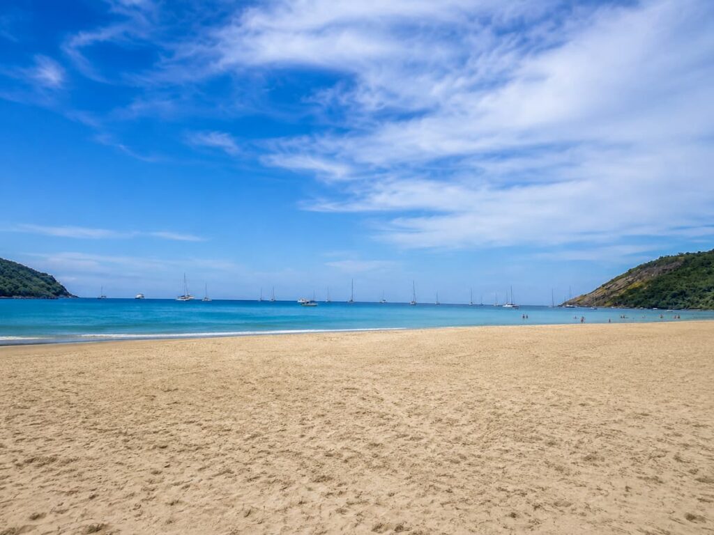 Wide sandy shoreline and anchored yachts at Nai Harn Beach in southern Phuket