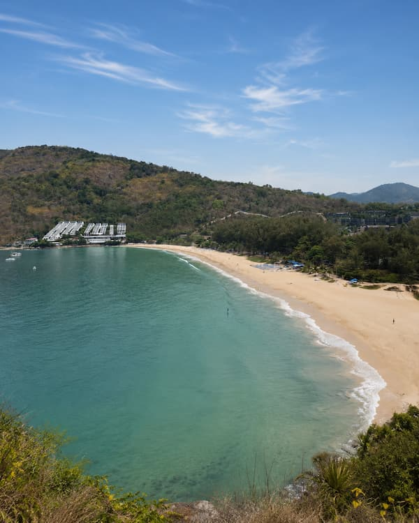 Elevated view across Nai Harn Beach and its forested hills, featured in a Phuket travel guide