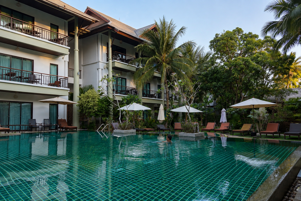 Swimming pool, palm trees and balcony rooms at Navatara Phuket Resort in Rawai, featured in our Phuket travel guide.