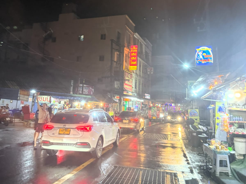 Patong weather after evening rain, with traffic, restaurants and street lights reflected across a wet road in central Patong.