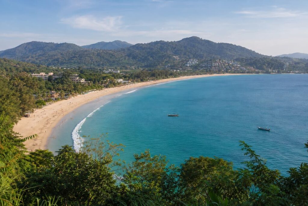 Broad sandy beach and forested coastline in Phuket, Southern Thailand