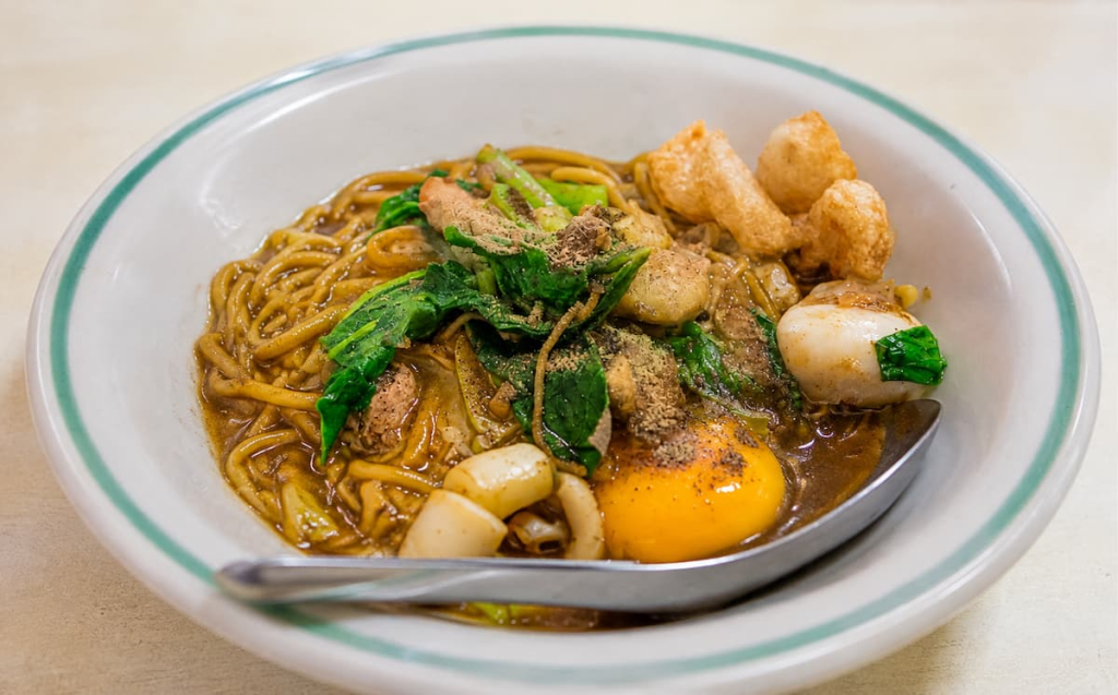 Phuket Hokkien mee with thick yellow noodles, seafood, greens and egg, featured in our Phuket travel guide.