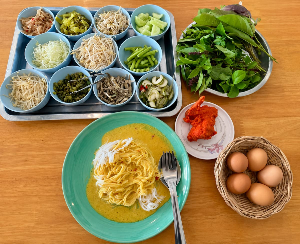 Phuket khanom jeen rice noodles with Southern Thai curry, fresh vegetables, pickles, boiled eggs and fried chicken.