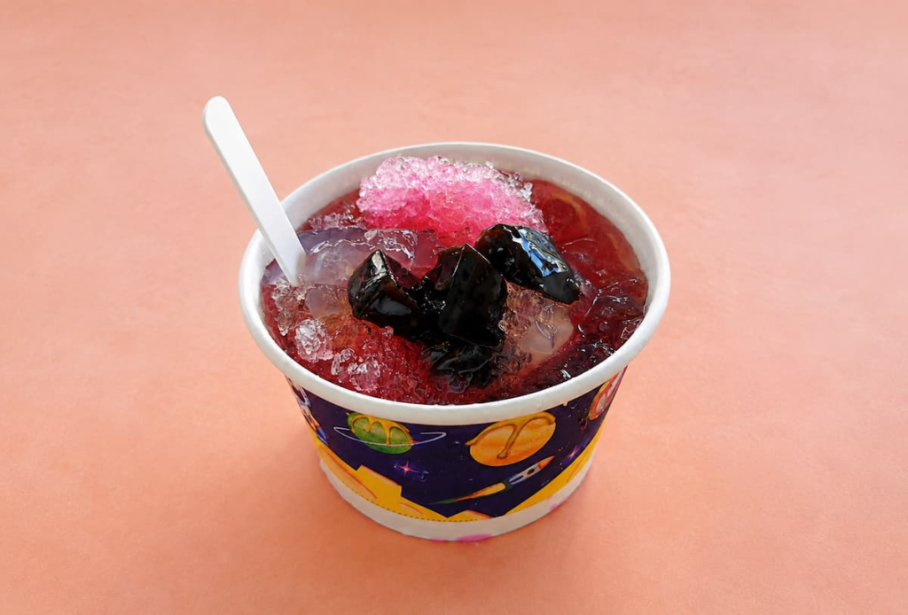 Phuket oh aew dessert with translucent jelly, red beans, black grass jelly, crushed ice and red syrup.