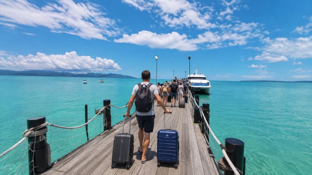 Travellers carrying luggage along a pier to board an island ferry in Southern Thailand.