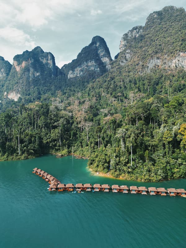 Southern Thailand travel guide view of floating raft houses beneath limestone mountains on Cheow Lan Lake in Khao Sok.