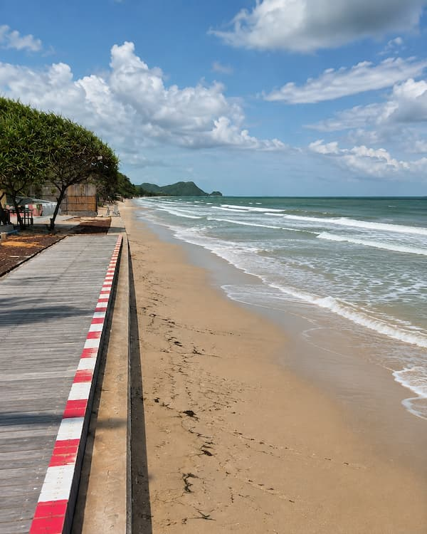Southern Thailand travel guide view along a quiet sandy beach and waterfront walkway in Khanom.