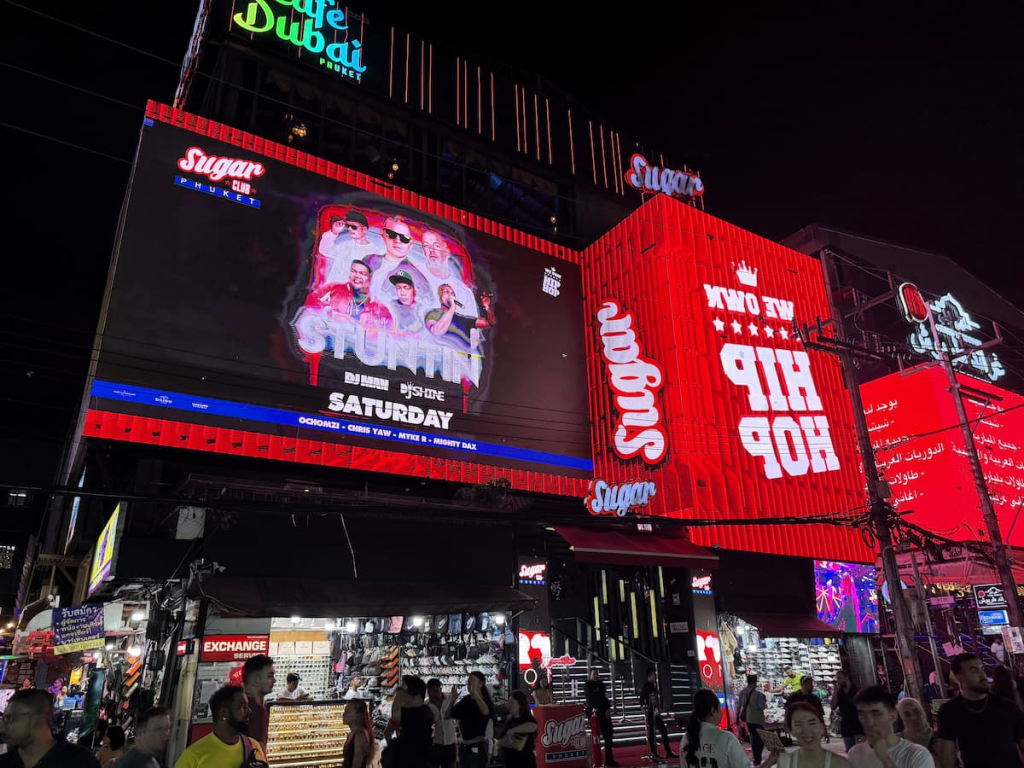 Thailand travel guide view of Sugar Club, illuminated signs and evening crowds on Bangla Road in Patong.