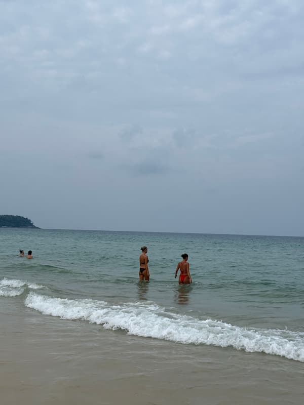 Travellers swimming in calm water at Karon Beach in Phuket, featured in our Karon Travel Guide.