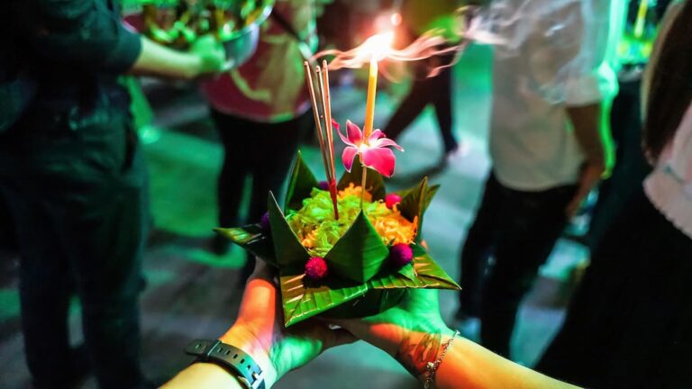 Thailand festivals featuring a traditional Loi Krathong offering decorated with flowers, incense and a candle