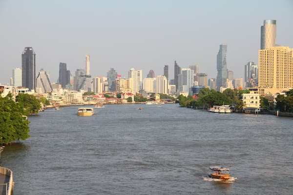 Thailand travel guide view of Bangkok’s skyline and boats along the Chao Phraya River.