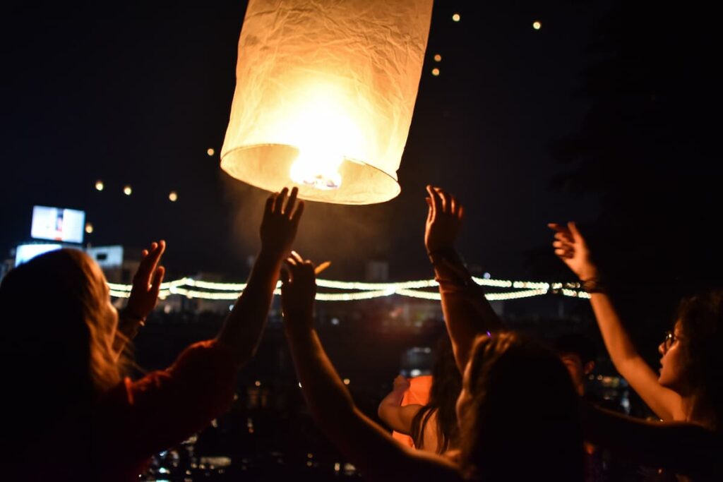 Yi Peng lantern festival in Chiang Mai with people releasing a traditional khom loi lantern