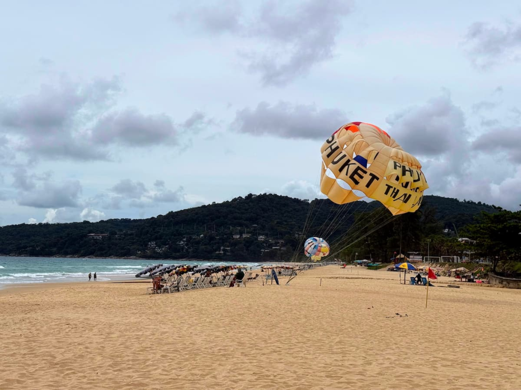 Parasailing activity on Karon Beach in Phuket, Thailand, beneath cloudy skies